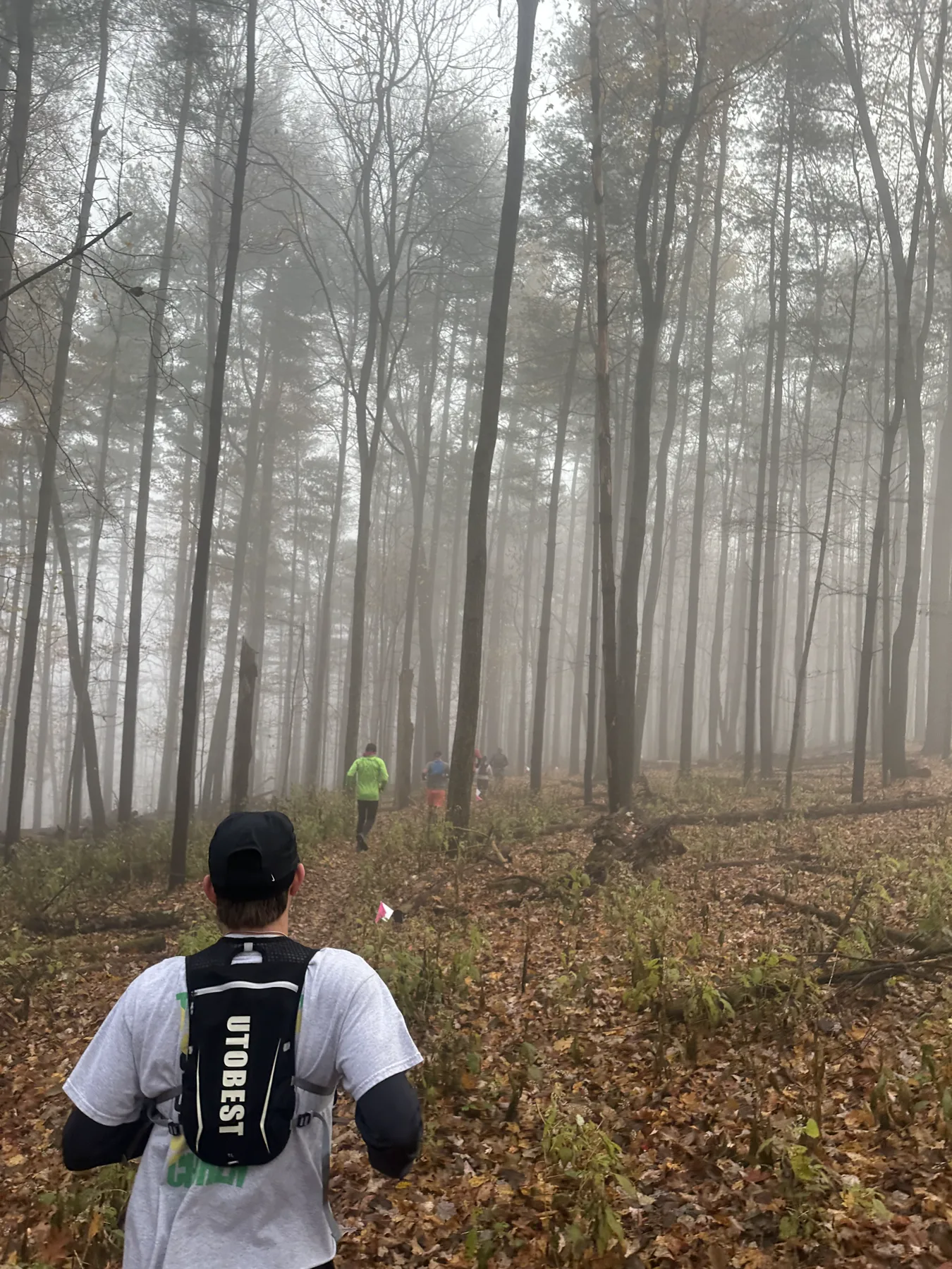 Logan Miller following runners through a foggy wooded trail race